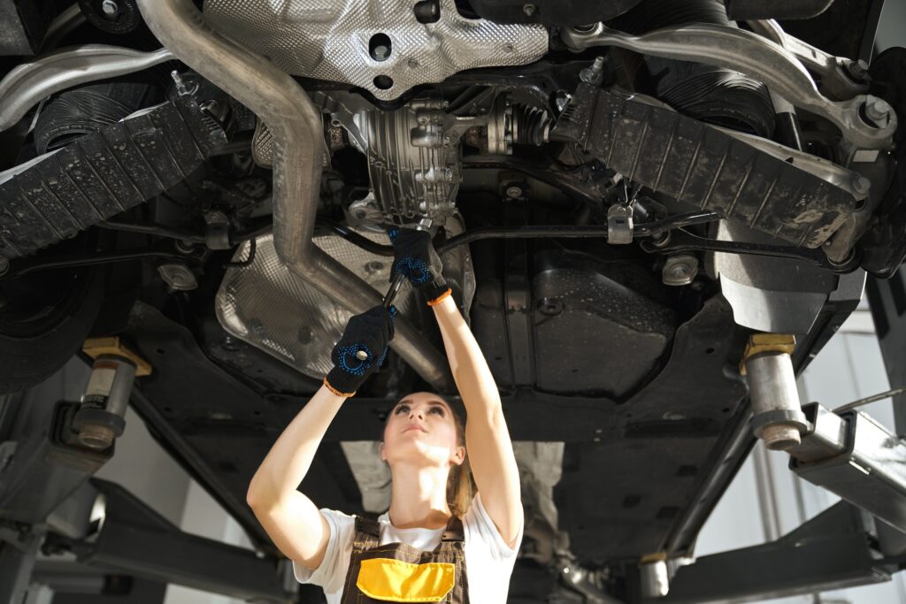 Young woman repairing automobile undercarriage